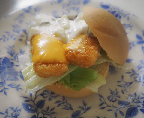 Foto van een broodje visfilet met remouladesaus en een plakje cheddar kaas